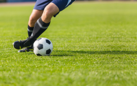man kicking soccer ball on green grass
