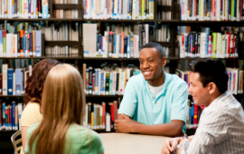 group of young adults sitting at a table in the library