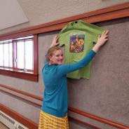 smiling young adult hanging a green tshirt on the wall