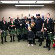 Celtic bagpipe & drum band, wearing kilts, posing with instruments