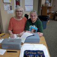 2 ladies volunteering at the book sale check out table