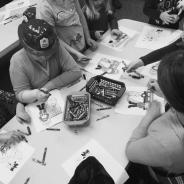 Children wearing firefighter hats and drawing pictures with crayons