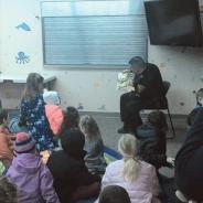 A close angle of a police officer reading to children