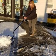 A woman shovels snow outside the library