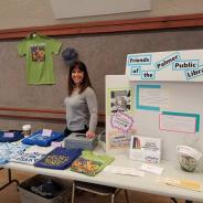 A woman at a table selling Friends of the Palmer Library merchandise