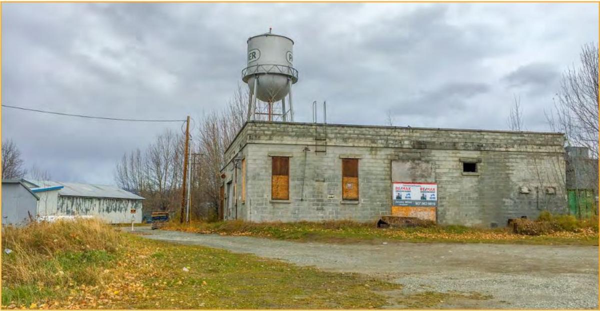 old concrete block with for sale sign and palmer water tower