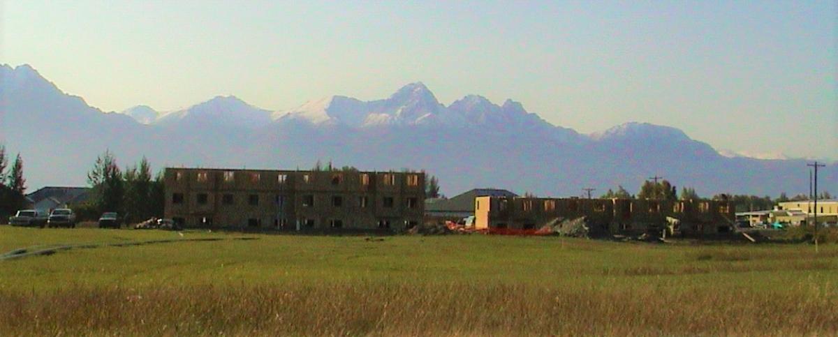 Partially constructed building in a field of grass with a mountain range in the background