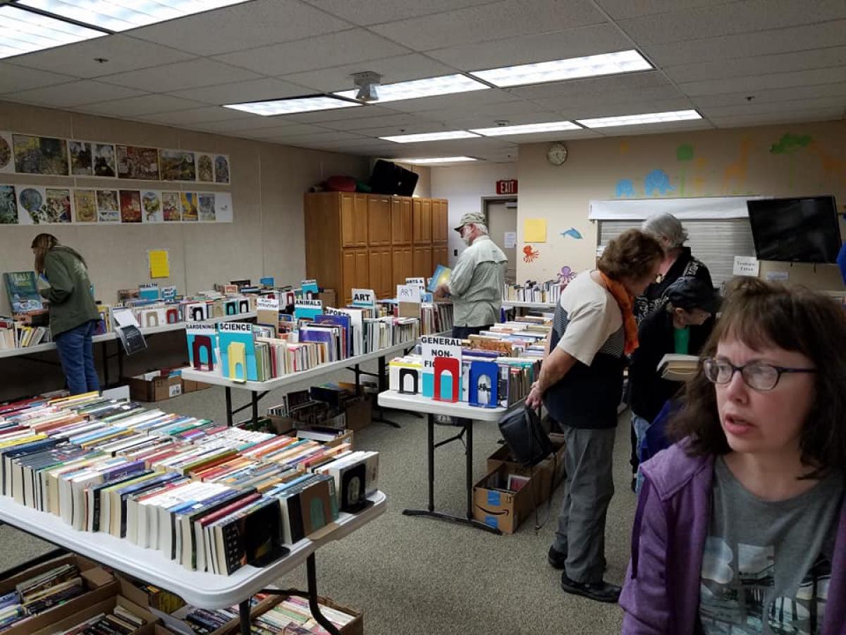 Two people looking at books, several tables filled with books for sale