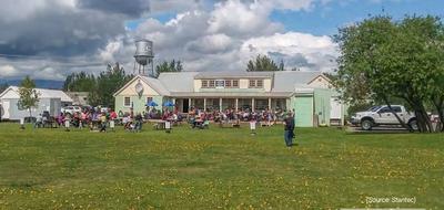 old style building with people congregating on the wide lawn. 